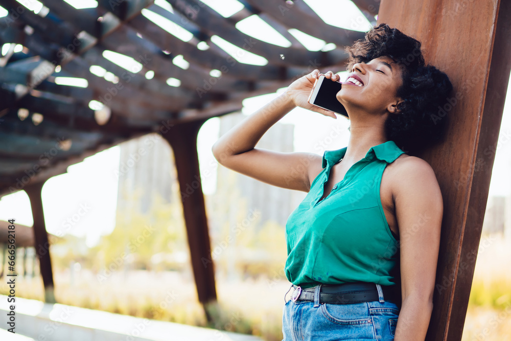 Cheerful African American hipster girl laughing during mobile phone conversation