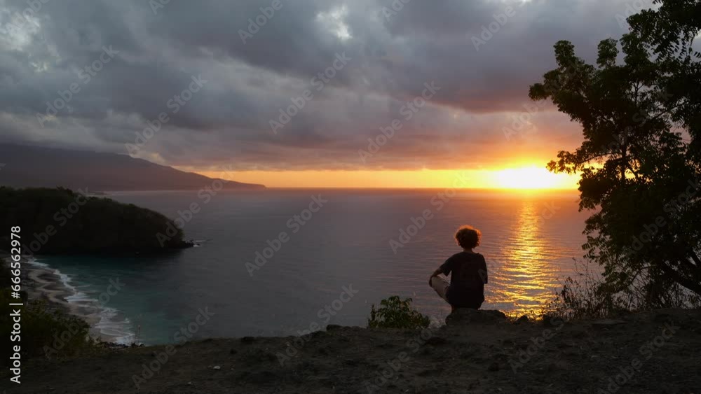 Wide shot of woman hiking, sitting on top of mountain and looking at sunset. Silhouette video of curly woman hiking to enjoy wild nature and camping. Concept hiking to recreation at exciting sunset Wide shot of woman hiking, sitting on top of mountain and looking at sunset. Silhouette video of curly woman hiking to enjoy wild nature and camping. Concept hiking to recreation at exciting sunset