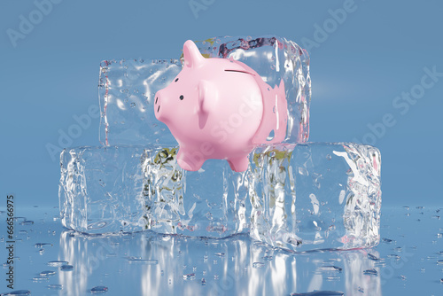 Fotografie Pink piggy bank partially in an ice cube on blue background