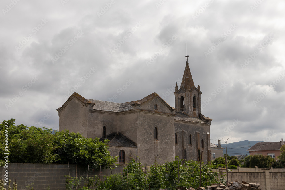 Historic Stone Church Under a Cloudy Sky in a Small Town