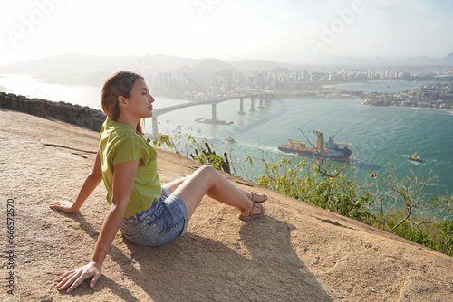 Beautiful woman sitting relaxed enjoying landscape on top of mountain at sunset photo