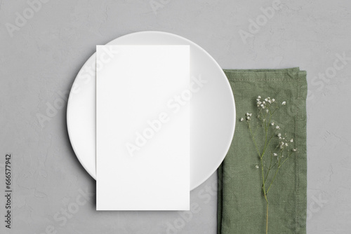 Wedding paper blank menu card mockup on white plate and napkin with flowers, top view, copy space