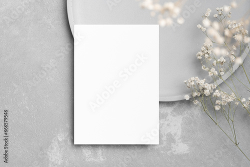 Blank paper wedding invitation card mockup with gypsophila flowers decor, copy space on grey concrete background