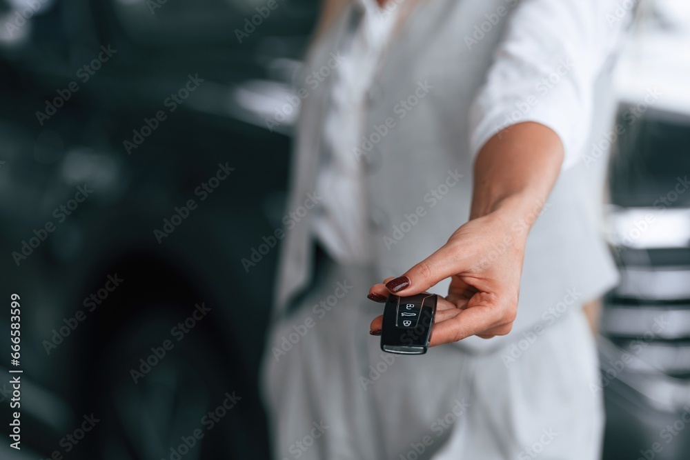 Woman is near the modern automobile in car dealership salon