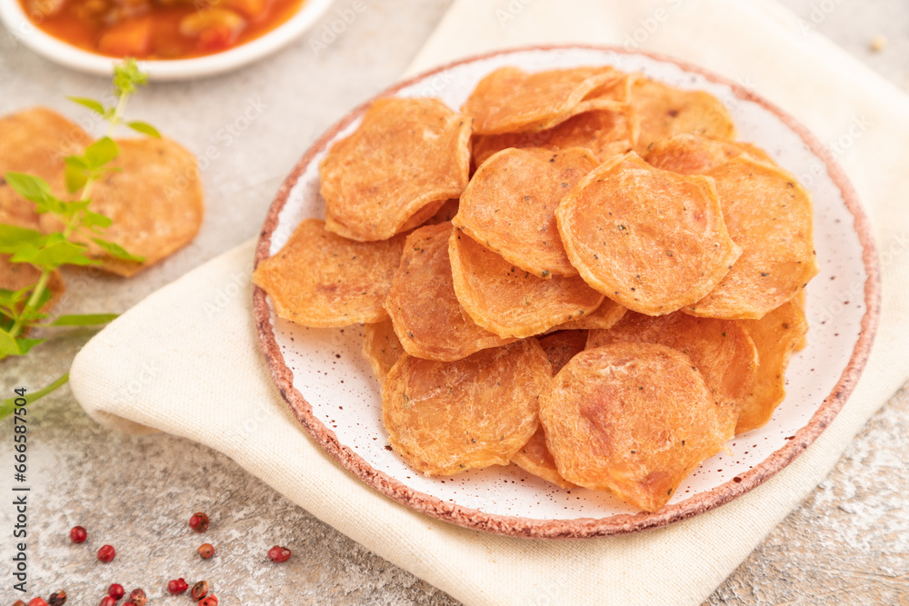 Slices of dehydrated salted meat chips on gray concrete, side view, selective focus Slices of dehydrated salted meat chips on gray concrete, side view, selective focus