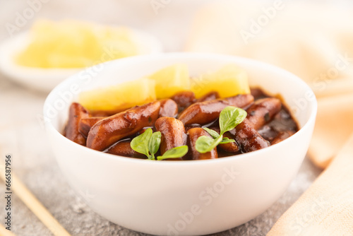 Tteokbokki or Topokki, fried rice cake stick, on gray concrete, side view, selective focus