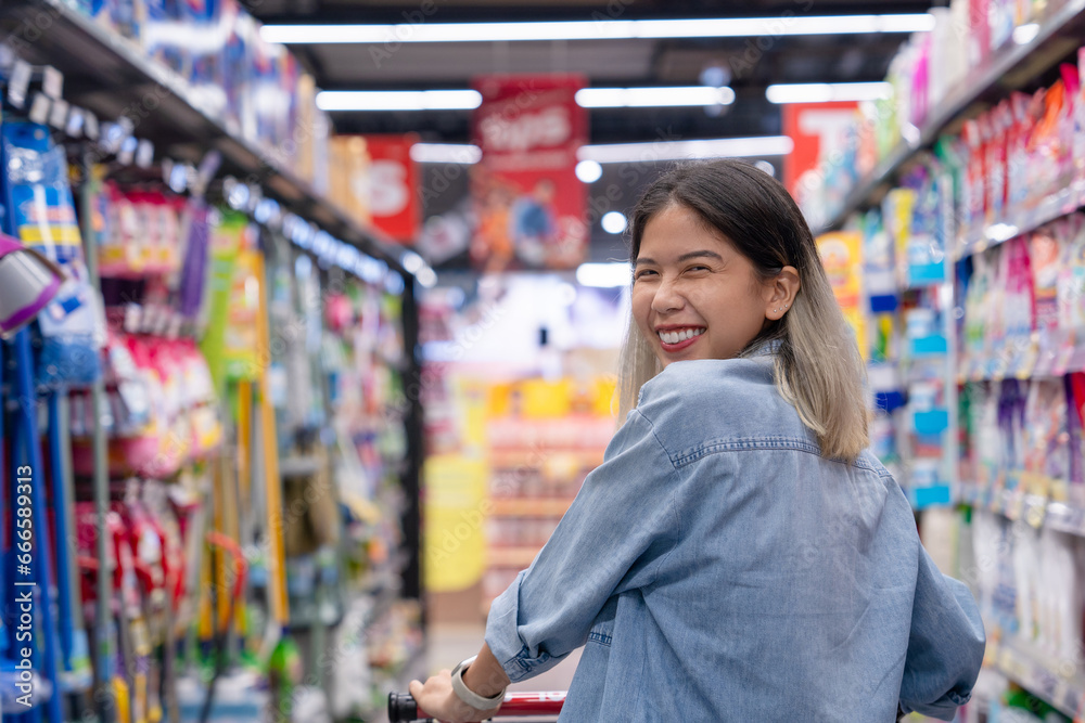 Happy young Asian woman walking in the supermarket. View from behind as she looks at the product.