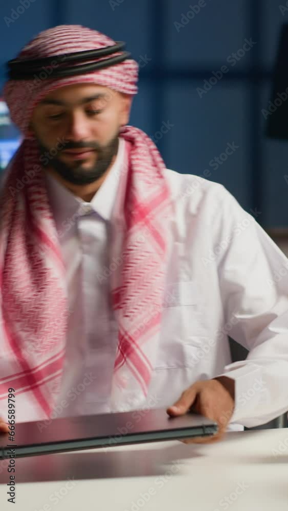 Vertical video Muslim entrepreneur starting his day working from home, opening laptop, surfing the net. Middle Eastern man arriving in personal apartment office with cup of coffee, answering emails Vertical video Muslim entrepreneur starting his day working from home, opening laptop, surfing the net. Middle Eastern man arriving in personal apartment office with cup of coffee, answering emails