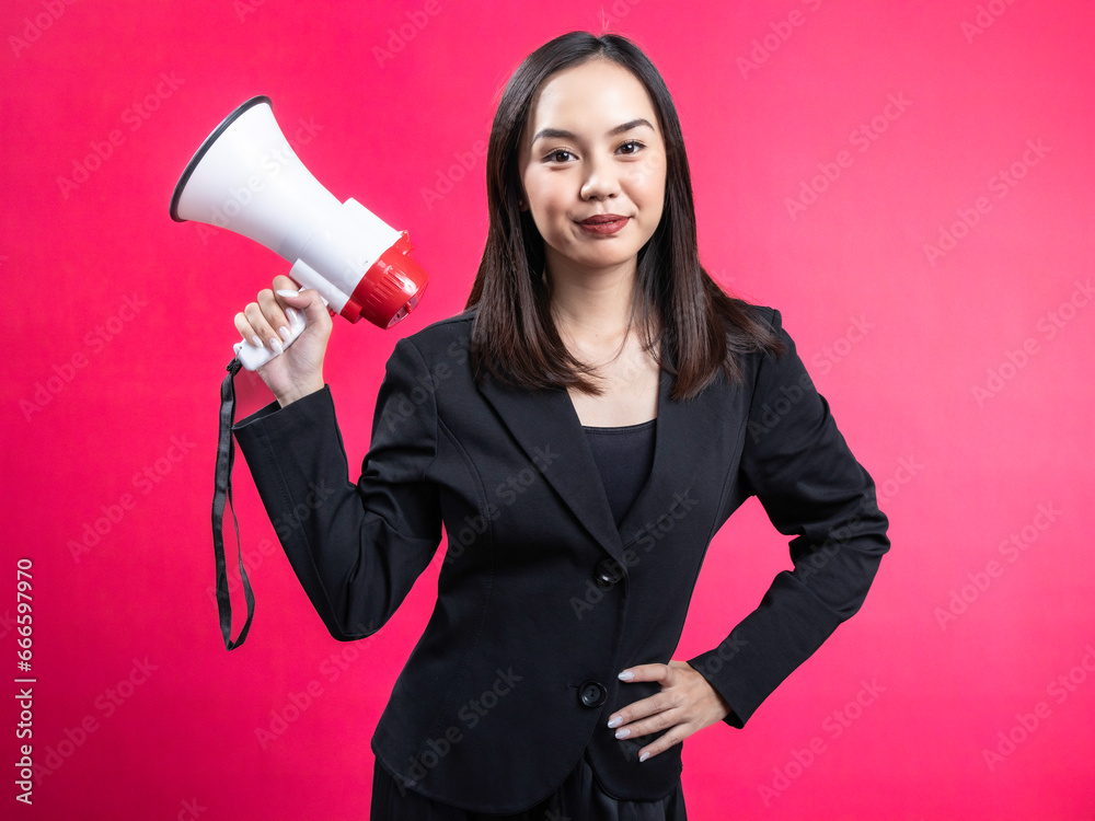 Portrait of an Asian Indonesian woman wearing a black work shirt, using a megaphone, and posing. Isolated against a magenta background Portrait of an Asian Indonesian woman wearing a black work shirt, using a megaphone, and posing. Isolated against a magenta background