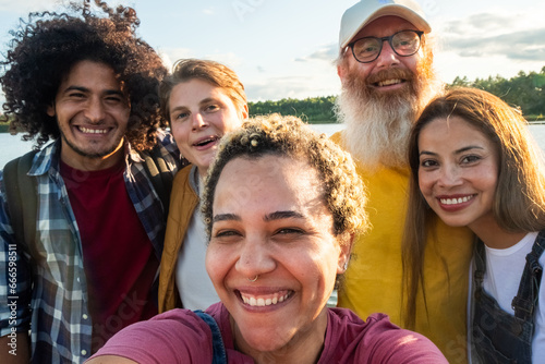 Wanderlust lifestyle, selfie, Multiracial young group of trendy people having fun together on vacation - Diverse millennial friends taking selfie portrait together while enjoying free time on a forest #666598511
