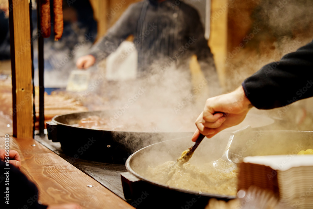 Process of cooking street food outdoors. Frying pan with fried dishes. Christmas Fair at Wroclaw main square Process of cooking street food outdoors. Frying pan with fried dishes. Christmas Fair at Wroclaw main square