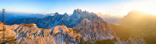 Panoramic, aerial view from Tre Cime di Lavaredo of the illuminated peaks of the Cime Eotvos mountain massif, with the three thousanders Punta Sorapis and Antelao in the background, Dolomites, Italy.  photo