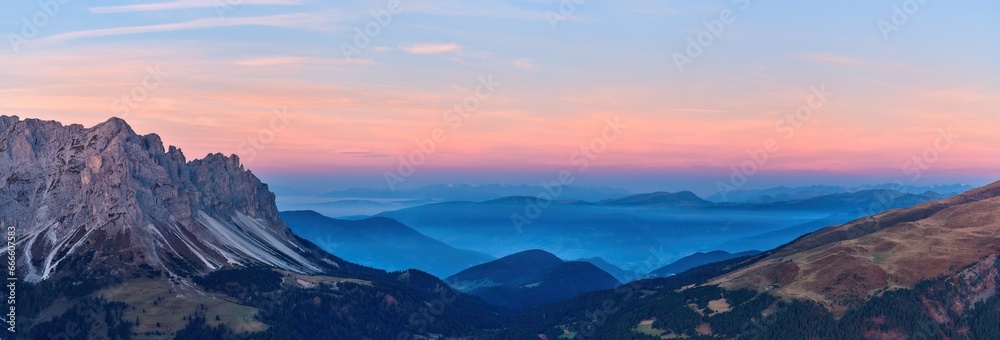Dawn over  Passo delle Erbe pass with the Dolomites peaks in the background. Shades of blue and orange, aerial panoramic view from high altitude.