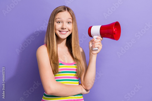 Photo portrait of cute teen blonde woman hold megaphone announce smile wear trendy striped clothes isolated on purple color background