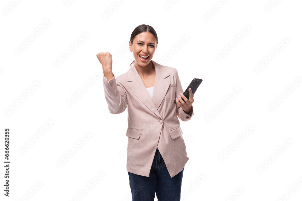young joyful leader business woman with a ponytail hairstyle dressed in a beige jacket holds a phone young joyful leader business woman with a ponytail hairstyle dressed in a beige jacket holds a phone