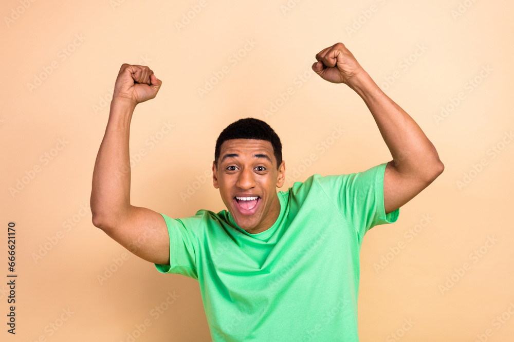 Fototapeta premium Photo portrait of handsome young male raise fists celebrate victory scream wear trendy green outfit isolated on beige color background