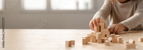 Kid playing with colorful wooden toy blocks. Little boy or girl building tower of block toys. Educational and creative toys and games for young children. Baby in white bedroom Copy space photo