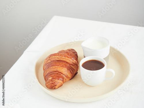 continental breakfast on the table croissant  coffee cup and milk jug