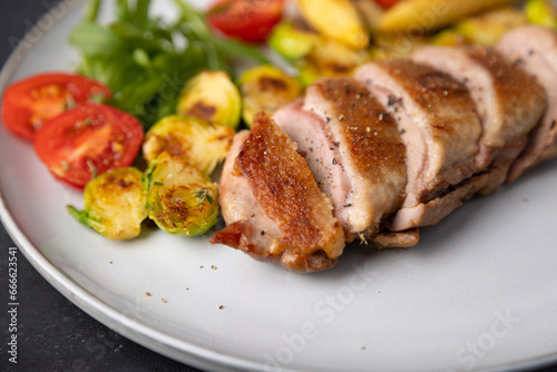 Grilled duck breast fillet with Brussels sprouts, mini corn, cherry tomatoes and arugula. Traditional Mediterranean cuisine. Selective focus, close-up.