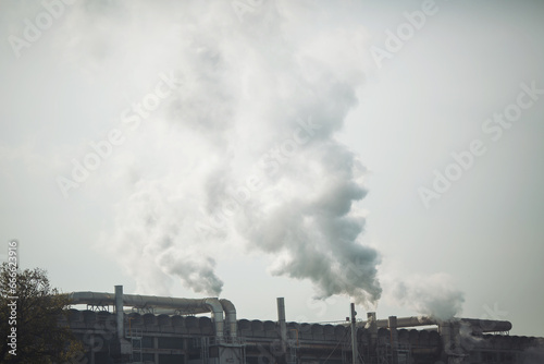 Smoke stack with smoke emission. Plant pipes pollute atmosphere. Industrial factory pollution, smokestack exhaust gases. Industry zone, thick smoke plumes. Climate change, ecology. © Cristina