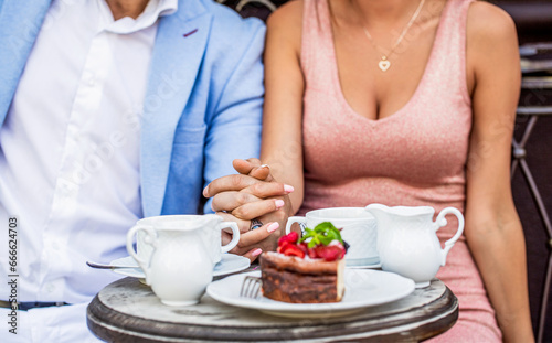 Romantic couple holding hands. Couple in having coffee in cafe. Drinking coffee. Happy romantic couple sitting in a cafe drinking coffee. Couple drinking cappuccino at bar coffee shop