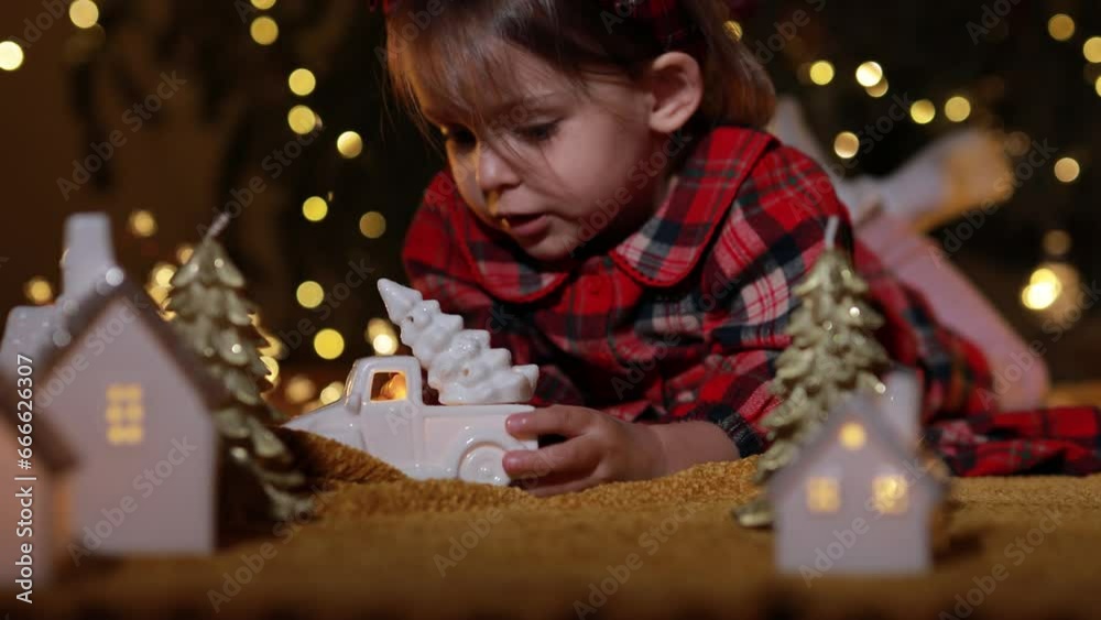 New Year's toys, decorations and garlands. A girl plays near the Christmas tree. Beautiful bokeh and light reflections. New Year's toys, decorations and garlands. A girl plays near the Christmas tree. Beautiful bokeh and light reflections.