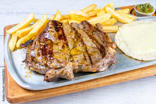 Tray of roast churrasco, accompanied by arepa with cheese, French fries and chimichurri