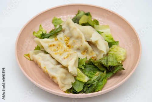Four Delicious Chinese Vegetable Dumplings with Lettuce on a Pink Plate