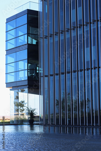Prédio de arquitetura contemporanea com fachada em vidro e metal e espelho dagua em sua lateral proporcionando ampla vista e entrada de luz em todos os ambientes photo