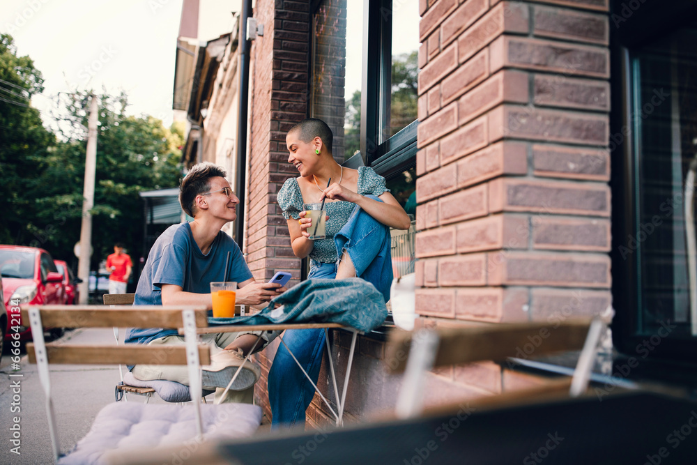 Lesbian couple talking and cuddling in cafe. Two beautiful young woman sitting next each other and sharing sweet moments.