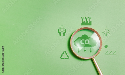 Magnifying glass with reduce CO2 emissions carbon symbol on green background for climate change to limit global warming and sustainable development and green business concept photo