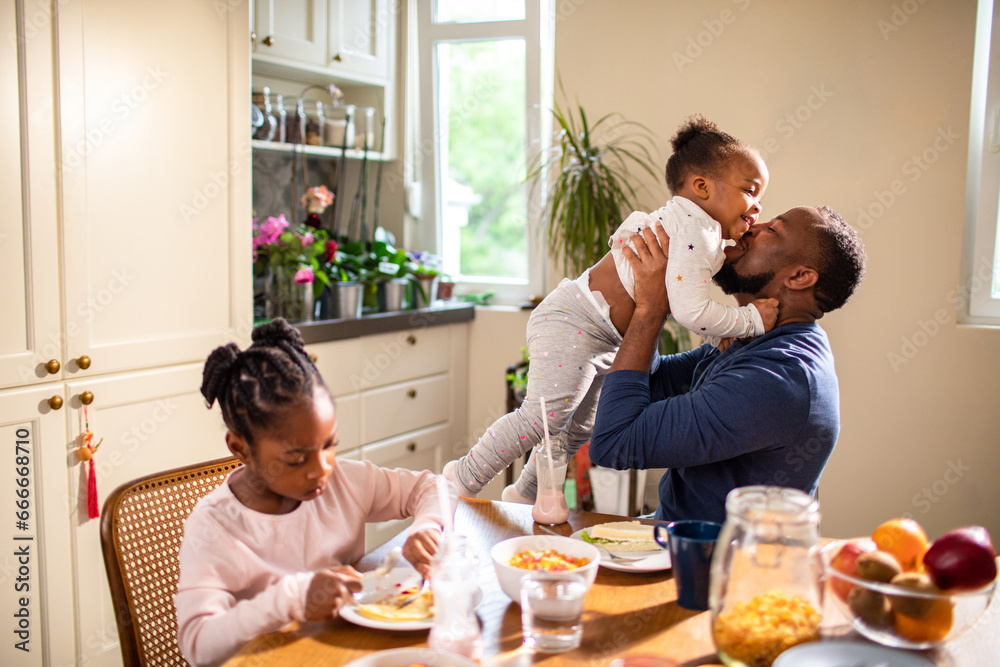 Happy young father playing with his daughter during breakfast in the kitchen Happy young father playing with his daughter during breakfast in the kitchen