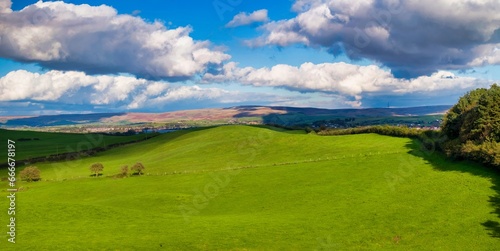 Panoramic view of green fields and autumn cloudy sky in Tandle Hill, Greater Manchester. 