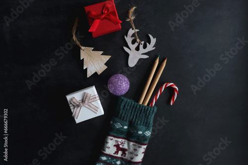 Christmas stocking filled with decorations, small presents, sweets and toys. Dark background, top view.