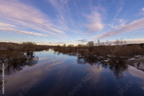 Spring dramatic landscape with overflowing river. Picturesque landscape with colorful sky over the spring river. Reflection in water.