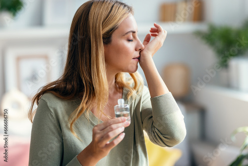 Fotografía Cheerful woman girl holding a bottle of essential oil while testing it sitting on a couch at home