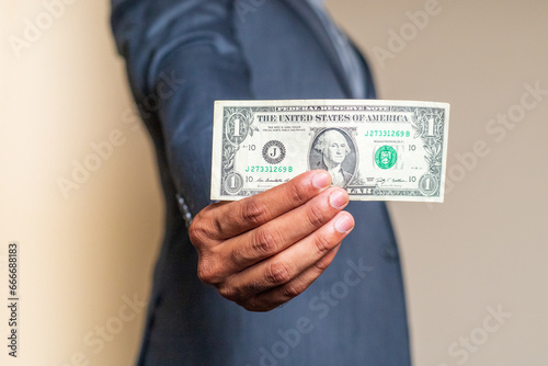 Businessman holding one US Dollar bill.