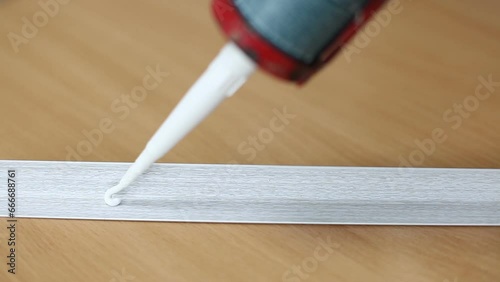 A male craftsman squeezes white silicone glue onto a plastic corner. Apartment renovation. photo