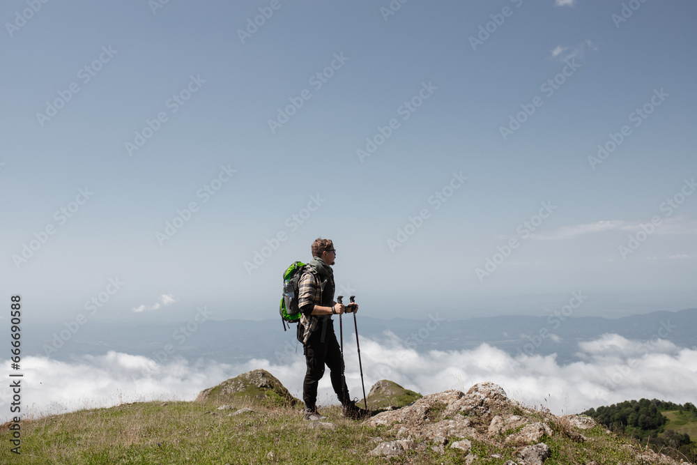 Portrait of a man in the mountains: summer sunny day, full-length portrait. The man enjoys the expansive view. High-quality photo for website design, postcards, banners, and travel product advertising