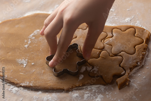 cuts out gingerbread cookies from dough, hand holds metal cutting.