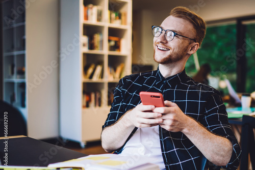 Cheerful freelancer using smartphone in modern workspace