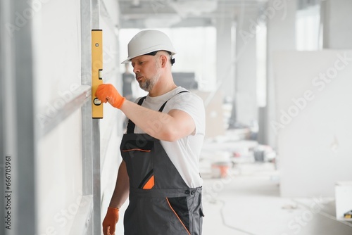 Man holding level against plasterboard, interior drywall. Attic renovation