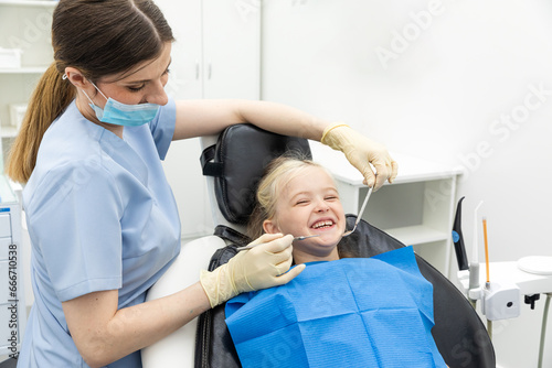 dentist  doctor examines the oral cavity of a little girl  uses a mouth mirror  baby teeth close-up  the concept of pediatric dentistry  dental treatment.