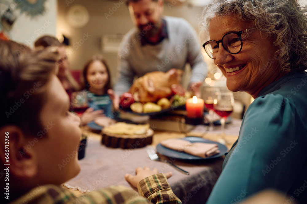 Happy grandmother and grandson talk during Thanksgiving family dinner at dining table. Happy grandmother and grandson talk during Thanksgiving family dinner at dining table.