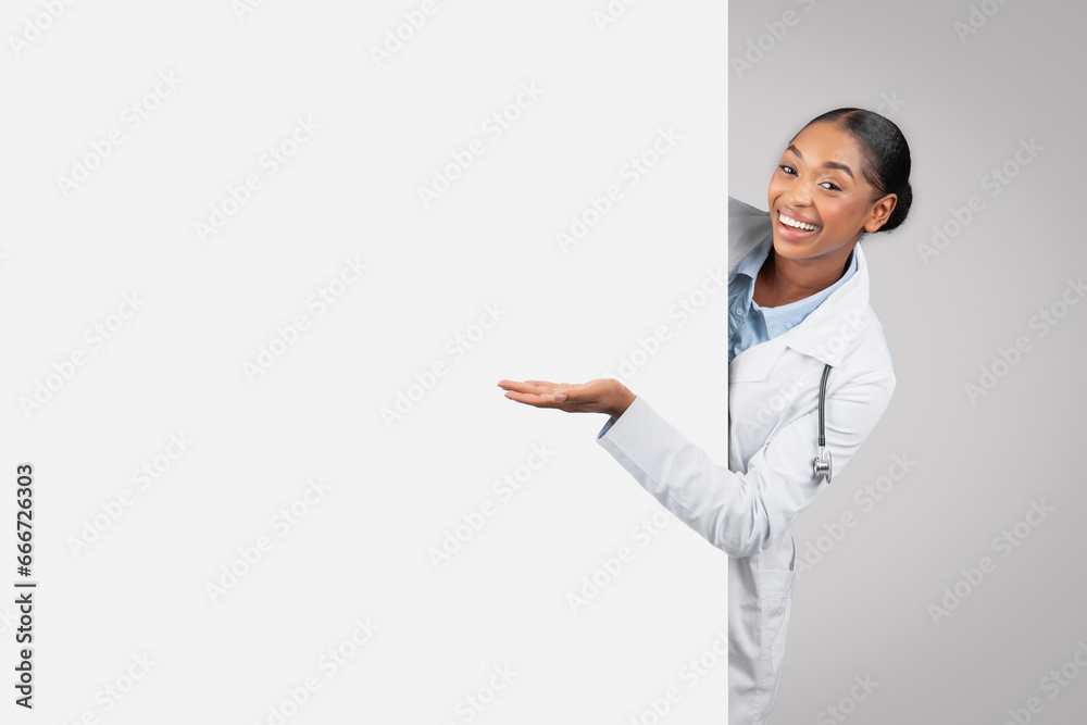 Positive millennial african american lady doctor with big banner point hand at copy space Positive millennial african american lady doctor with big banner point hand at copy space