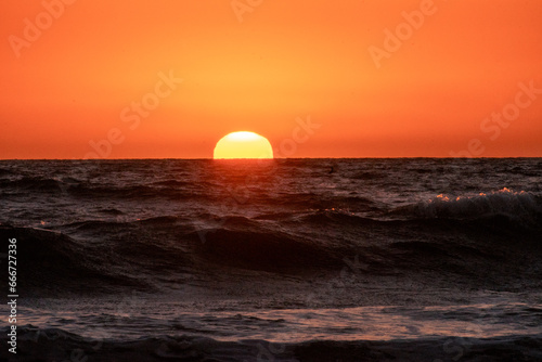 Fototapeta Naklejka Na Ścianę i Meble -  Sunset into the Pacific Ocean from a west coast beach in Southern California