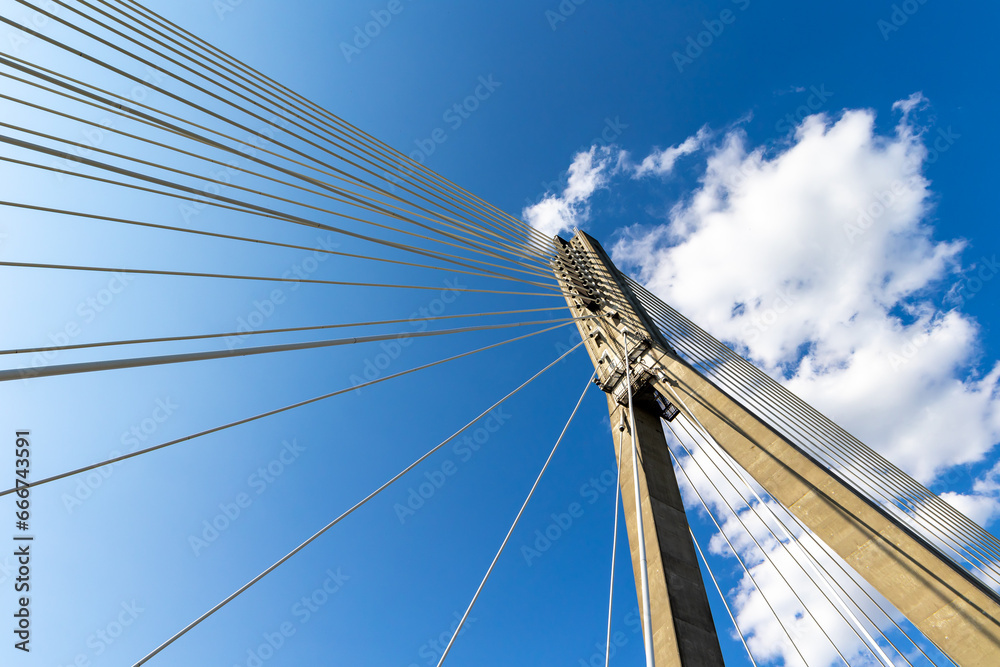 Obraz premium Fixing the ropes in the concrete pylon of the rope bridge. View of the bridge structures against the blue sky