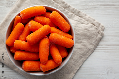 Raw Baby Carrots in a Bowl on a White Background, top view. Flat lay, overhead, from above.