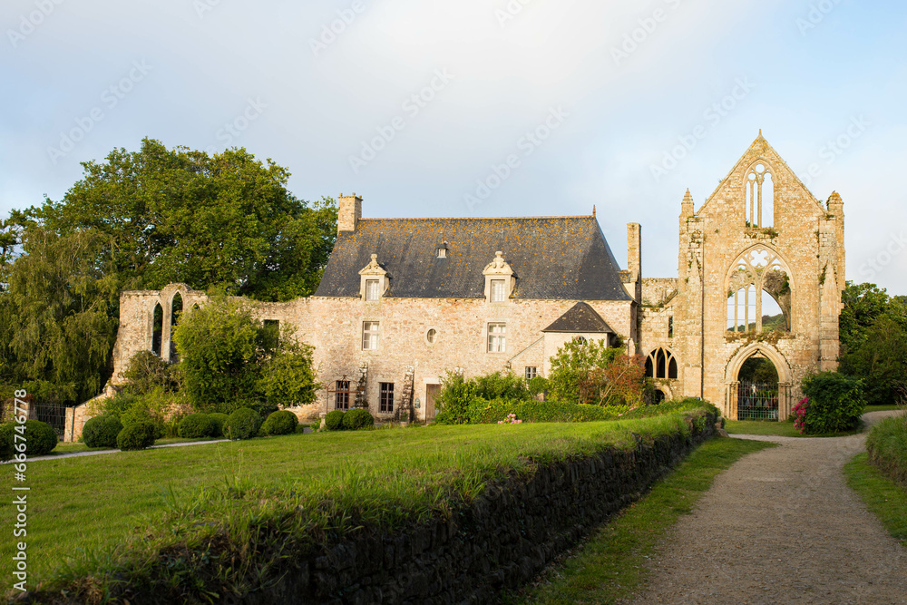The main facade and alleyway of Beauport Abbey, a roofless gothic building located in Paimpol, Cotes d'Armor, Brittany, France. August 2023, sunset 