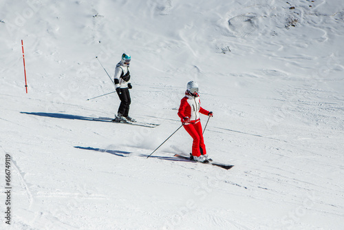 Learning ski. Skiing woman skier going downhill against snow on ski trail slope piste in winter. Good recreational female skier in red ski jacket.